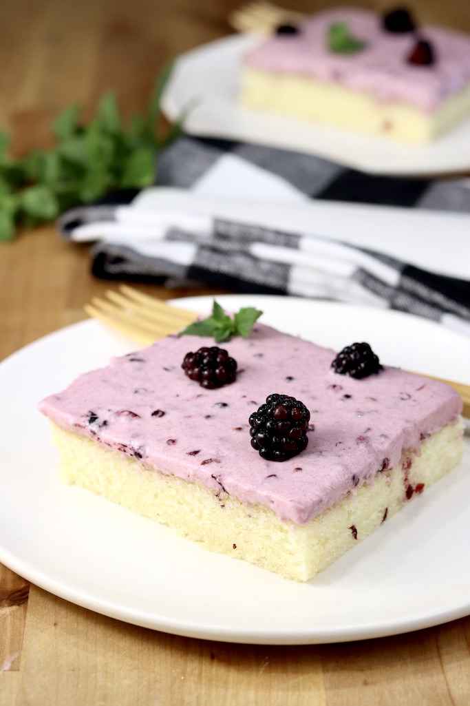 Blackberry Sheet Cake sliced on a white plate, another serving in background