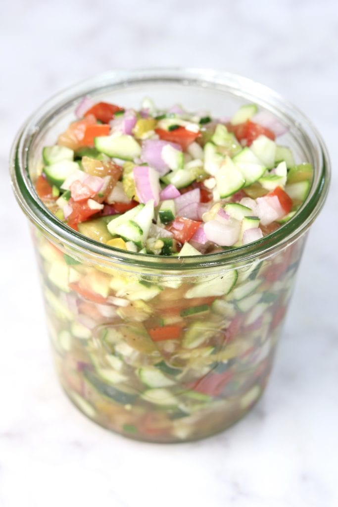 Cucumber Tomato Salad is one of the most refreshing and delicious dishes you can make this summer. Made with garden fresh cucumbers, tomatoes and onion all in a sweet and tangy dressing. Delicious served alongside grilled beef, pork, chicken or fish. Chopped cucumber tomato and onion salad in a weck jar