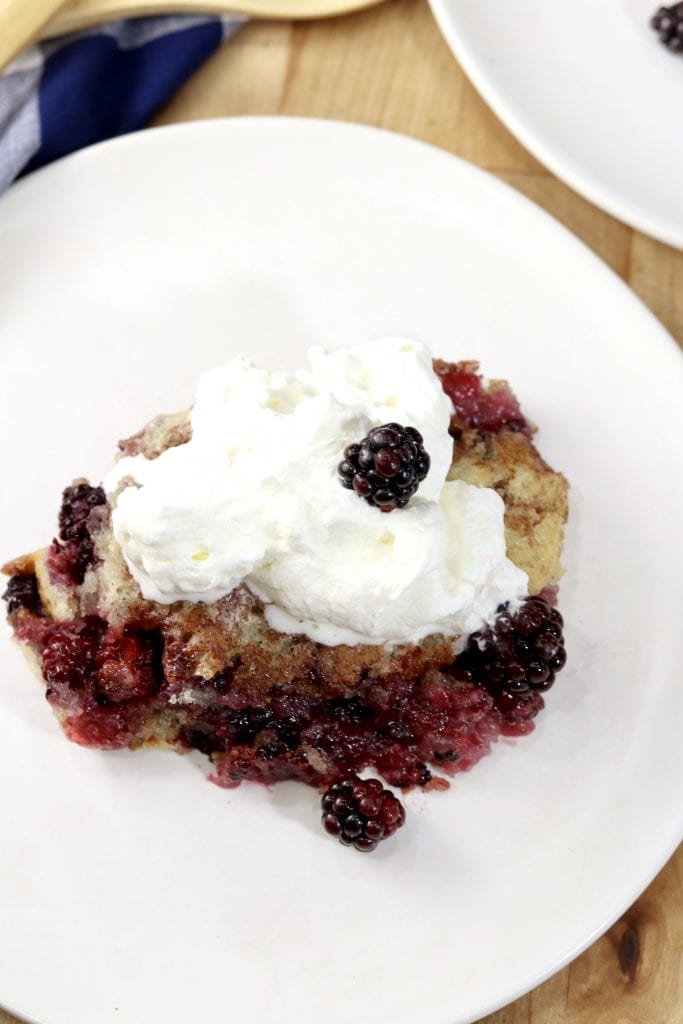 Blackberry cobbler with whipped cream on a white plate