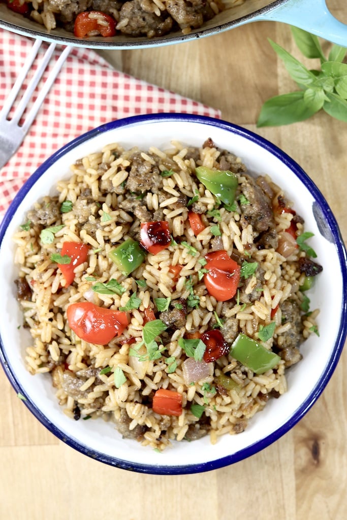 Bowl of sausage and pepper rice garnished with fresh herbs