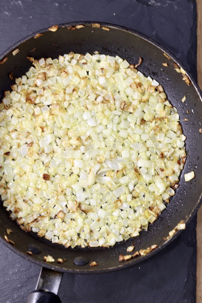 diced onions and garlic cooked in olive oil in a black skillet