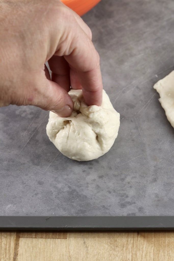 Making dessert bombs with biscuit dough, pinching together to form a ball