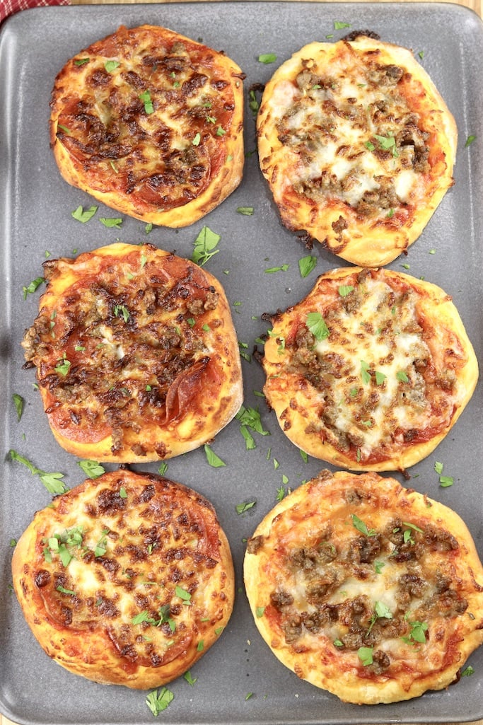 gray platter with 6 mini pizzas with pepperoni, sausage and cheese -overhead view