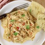 Plate of chicken spaghetti and garlic bread with a fork