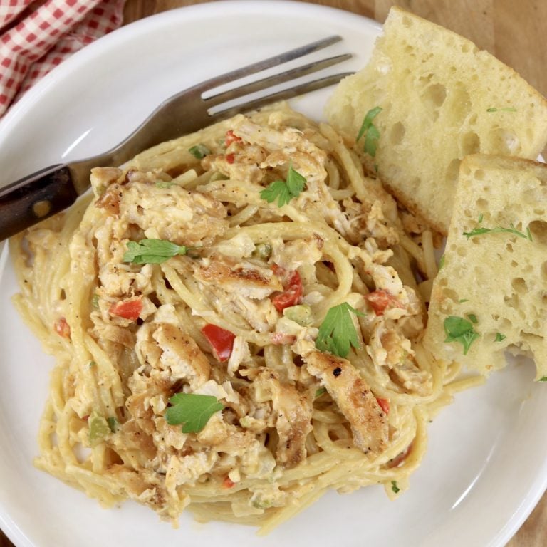 Plate of chicken spaghetti and garlic bread with a fork