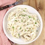 plate of fettuccine Alfredo overhead view with fork and red napkin