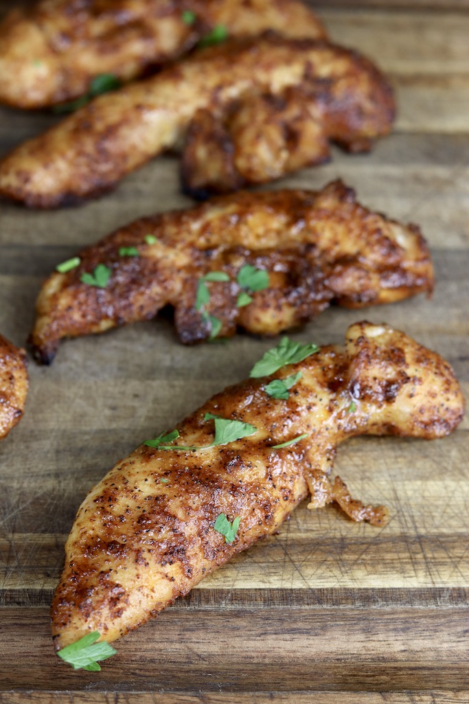 Grilled chicken tenders on a wood cutting board