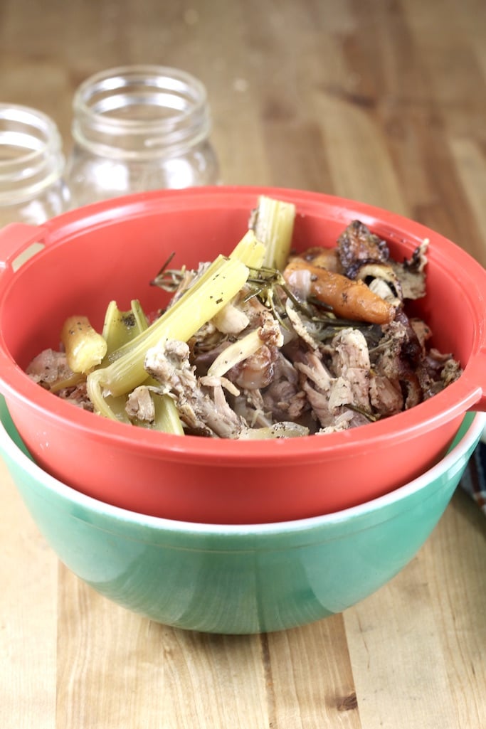Straining chicken broth with a red strainer into a green bowl