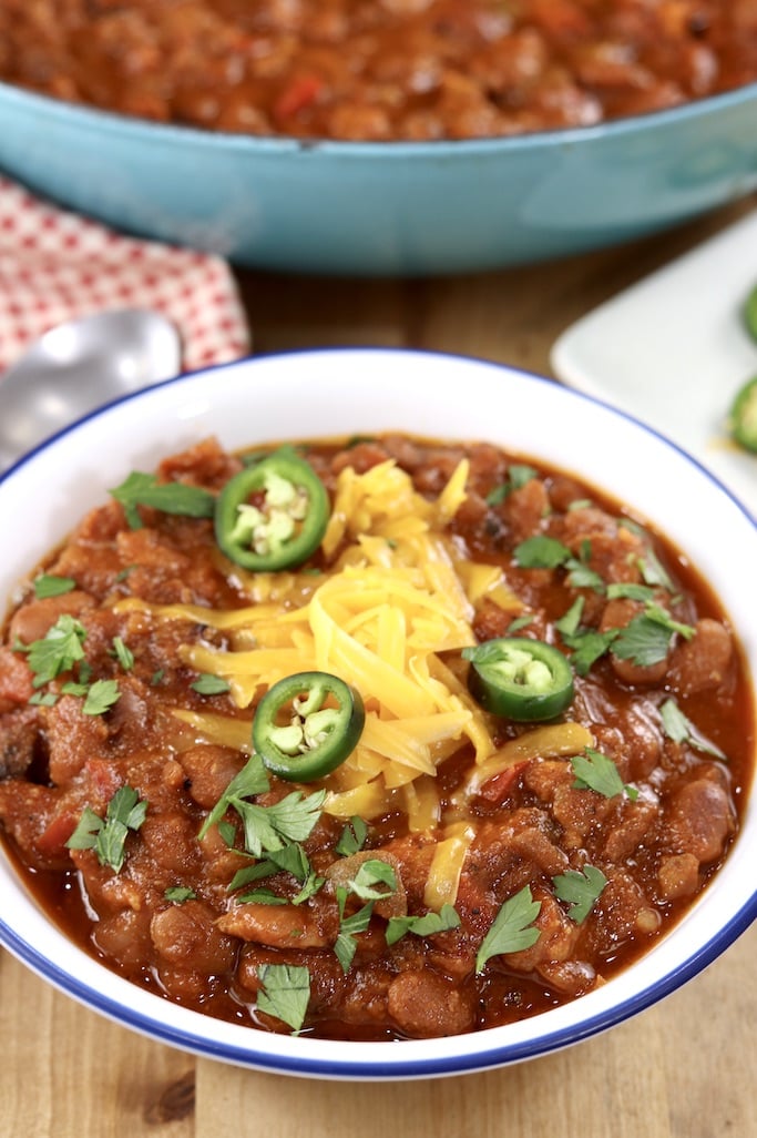 Smoked Pork Chili topped with cheese and jalapenos in a white bowl