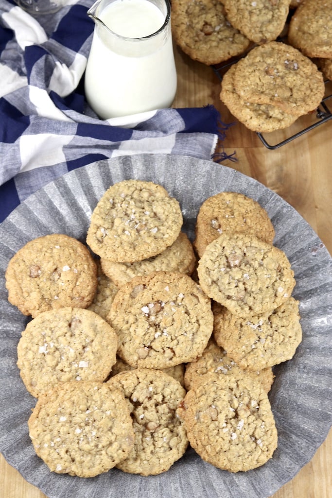 Platter of oatmeal cookies, with milk and wire rack of cookies in background