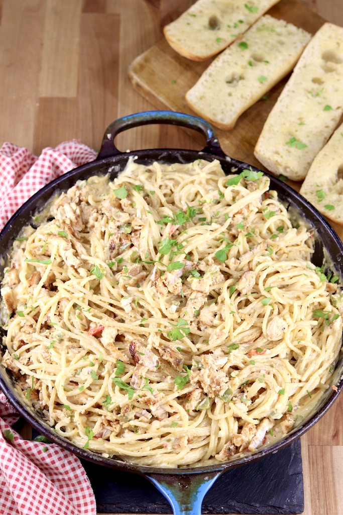 Skillet of chicken spaghetti, garlic bread off to the side