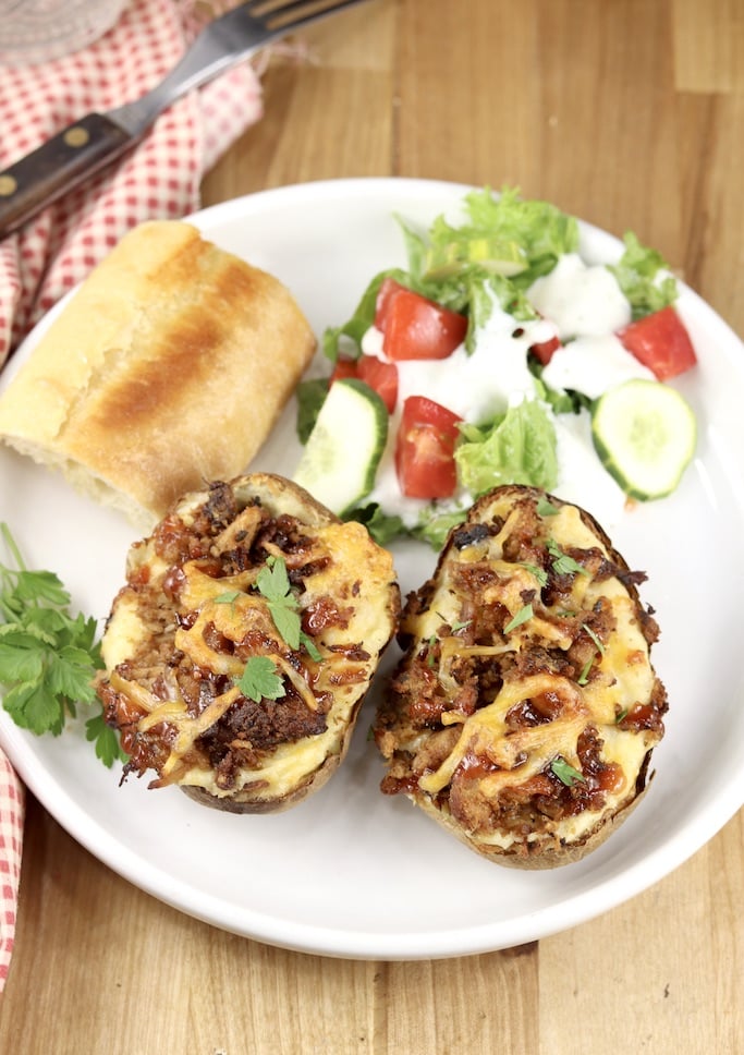 Plate with salad, bread and twice baked potatoes topped with pulled pork and bbq sauce