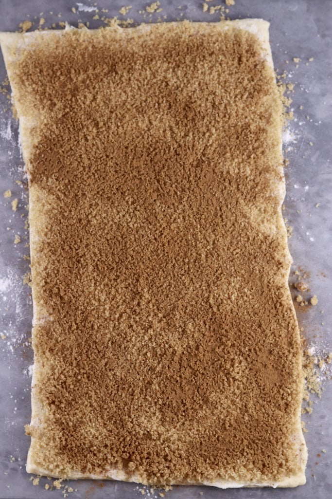 Cinnamon and brown sugar sprinkled over crescent dough rectangle for making cinnamon rolls