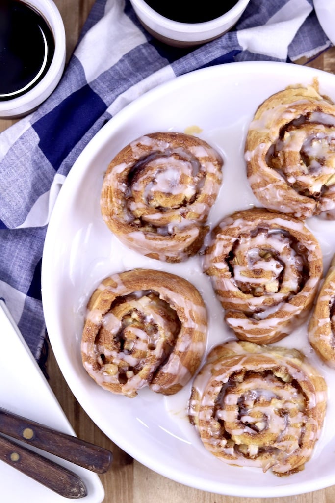 Overhead view of plate of apple cinnamon rolls, coffee in back ground in 2 cups