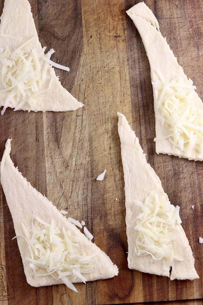 shredded cheese on crescent dough triangles