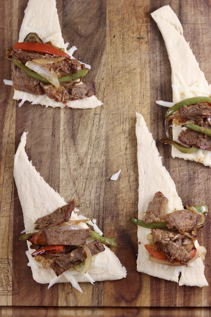 Filling crescent dough with cheese, roast beef peppers and onions