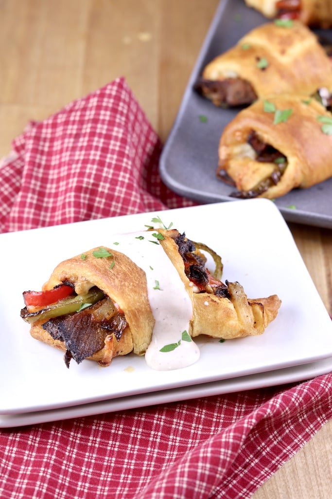 Air fryer cheesesteak with horseradish sauce drizzled over the top on a plate