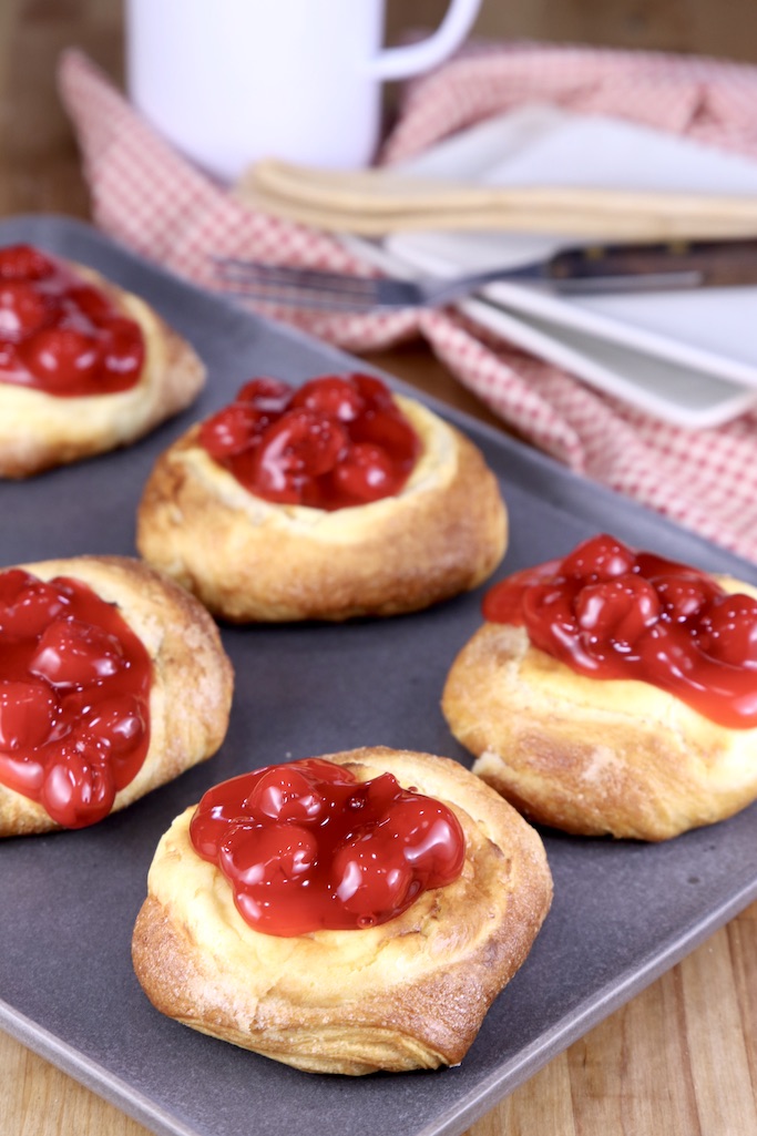 Cherry Cheese Danishes on a platter, red napkin and saucers in background