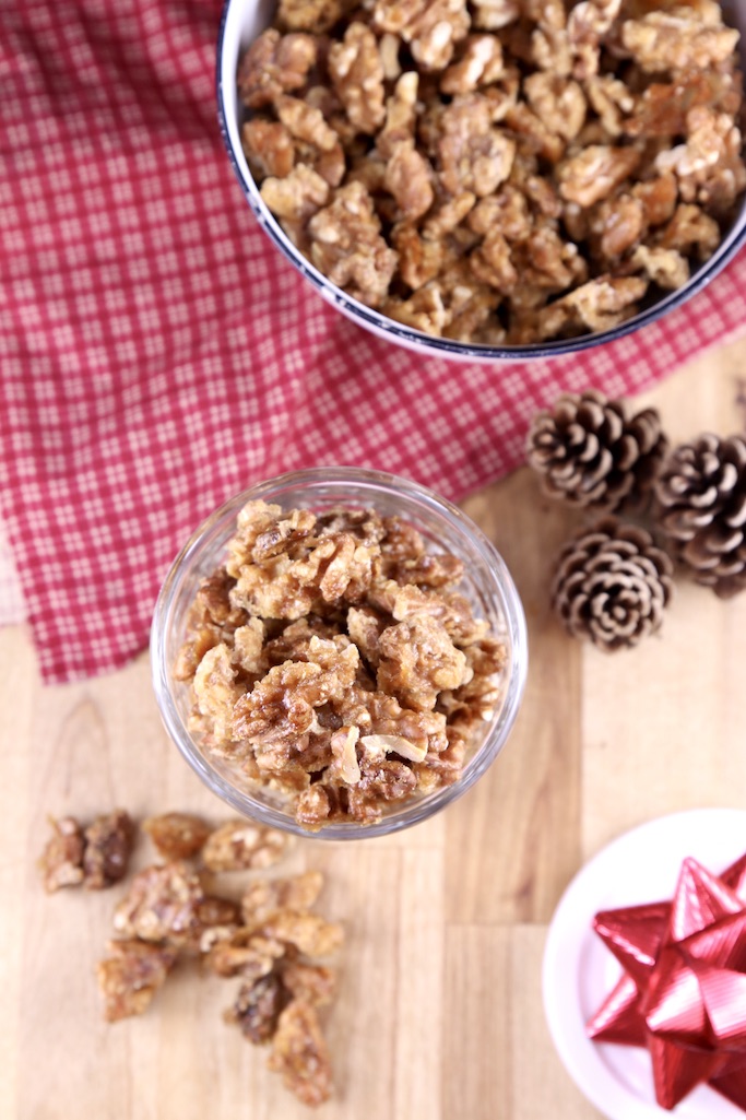 overhead view, candied walnuts in a jar and a bowl, pine cones on the table, red napkin and a few walnuts scattered