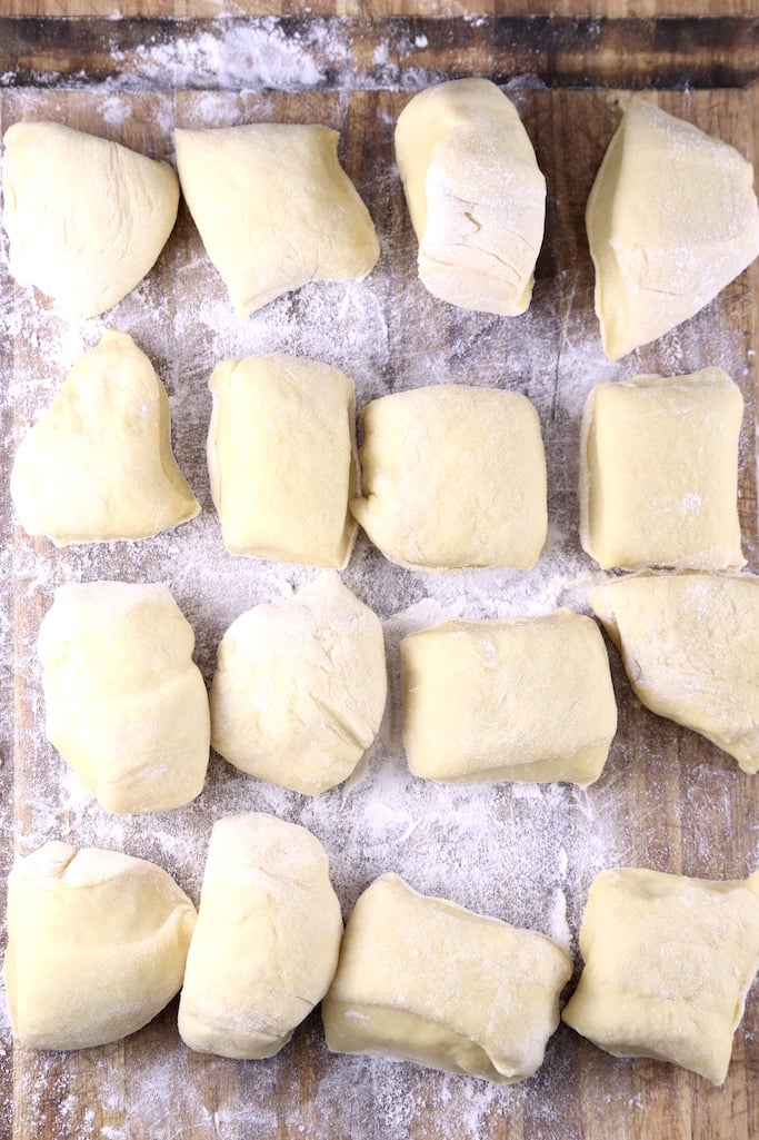 16 pieces of dinner roll dough on floured board
