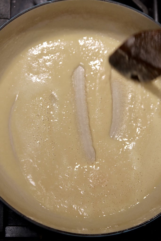 making a roux with butter and flour in a pan with a wood spoon