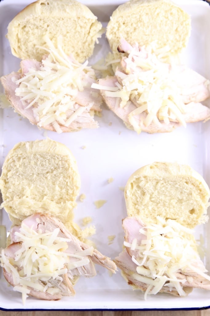 Sliced rolls with turkey slices and shredded cheese