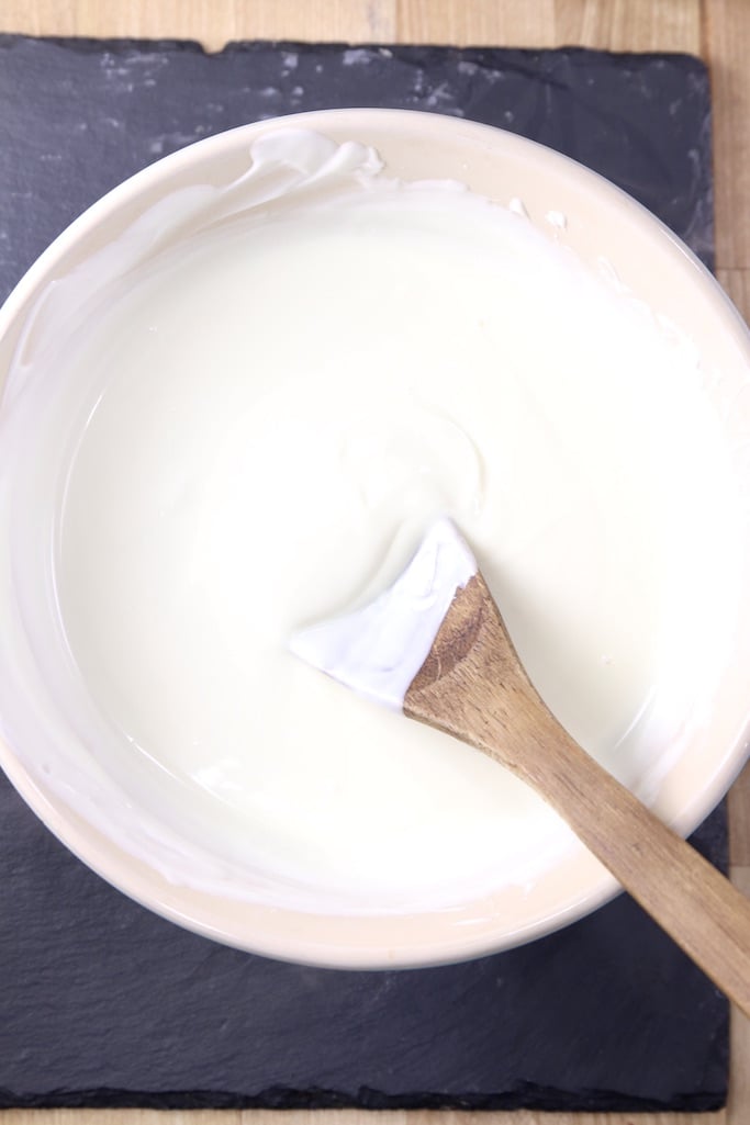 melted white wafers in a bowl with a wood spoon