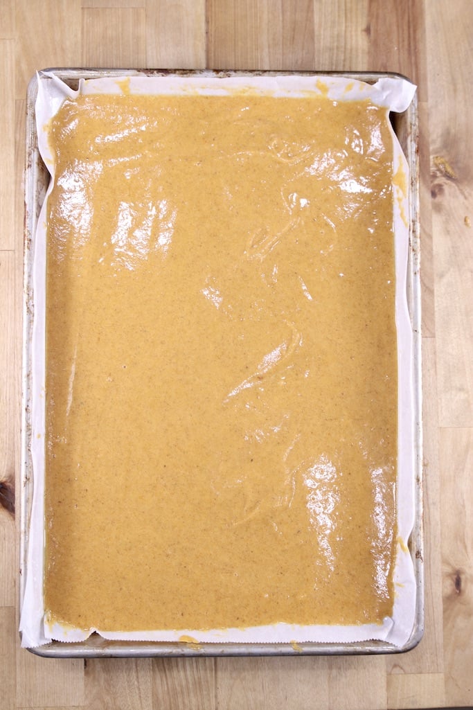 pumpkin cake batter in a parchment lined jelly roll pan