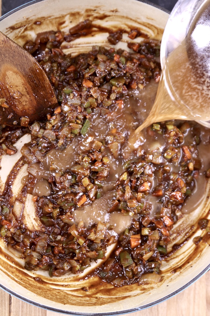 pouring broth into vegetable and roux mixture for soup