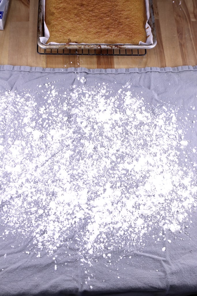 Gray towel sprinkled with powdered sugar for making pumpkin roll cake