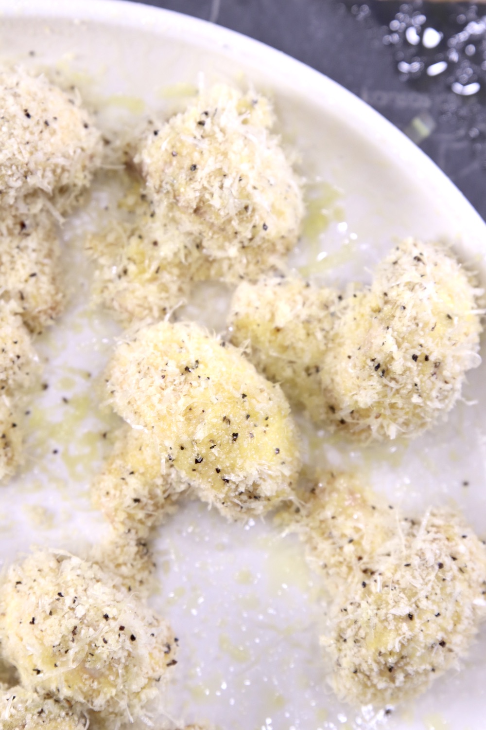 breaded mushrooms on a plate sprayed with olive oil for air fryer