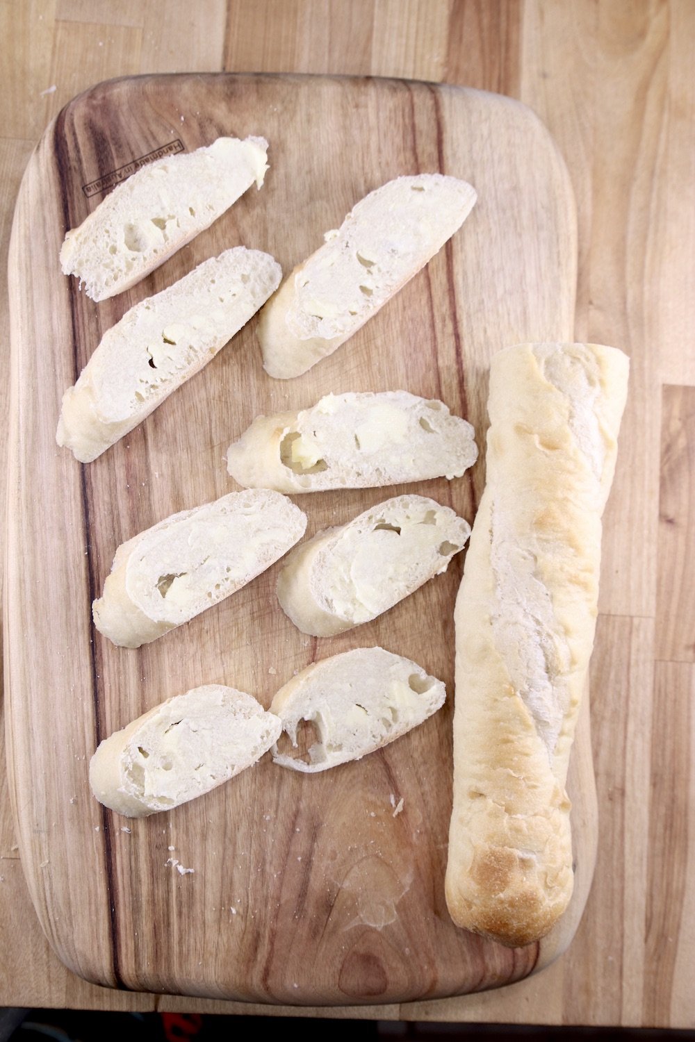 Baguette on a cutting board, half sliced
