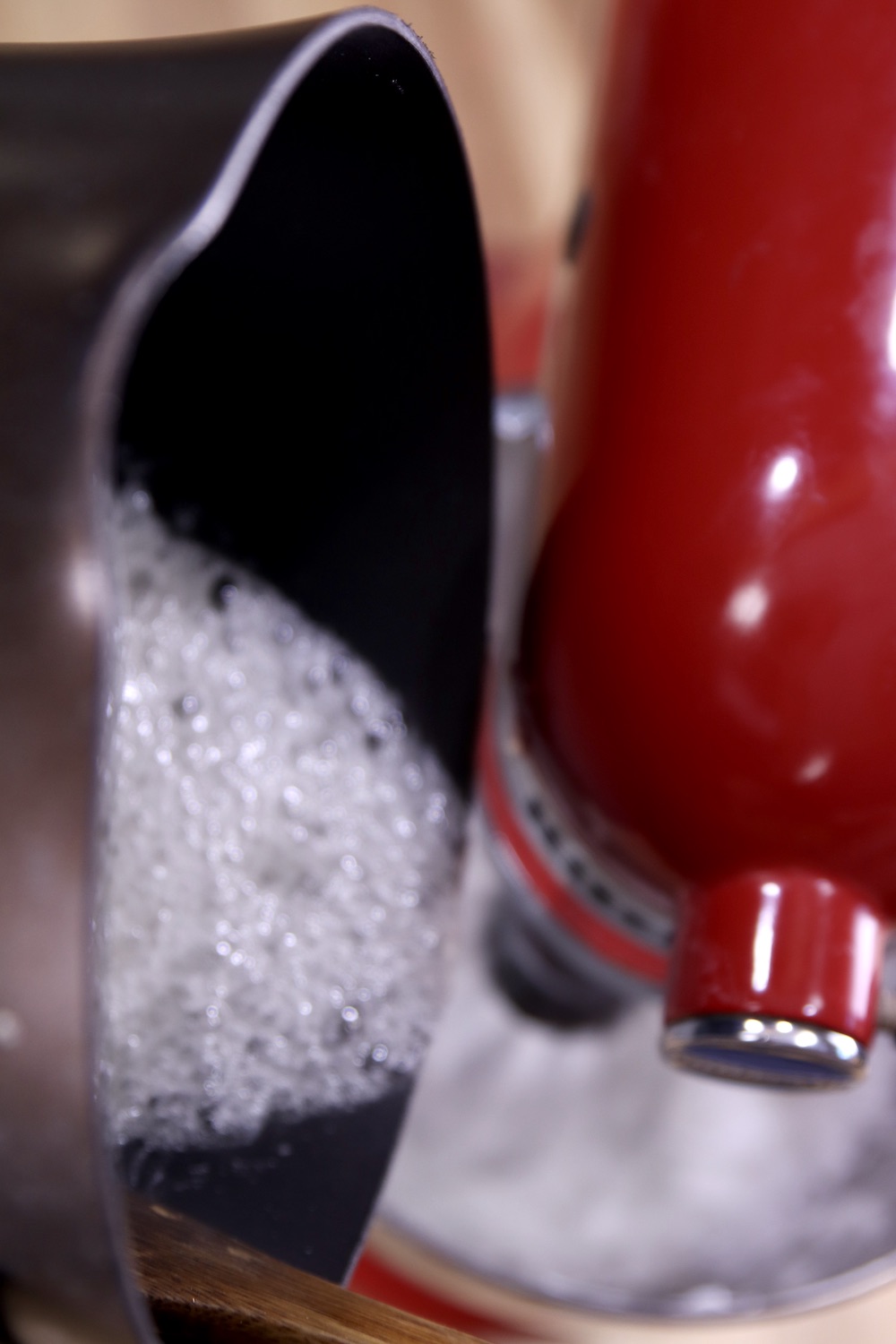 Pouring boiling syrup into mixer bowl of egg whites for icing