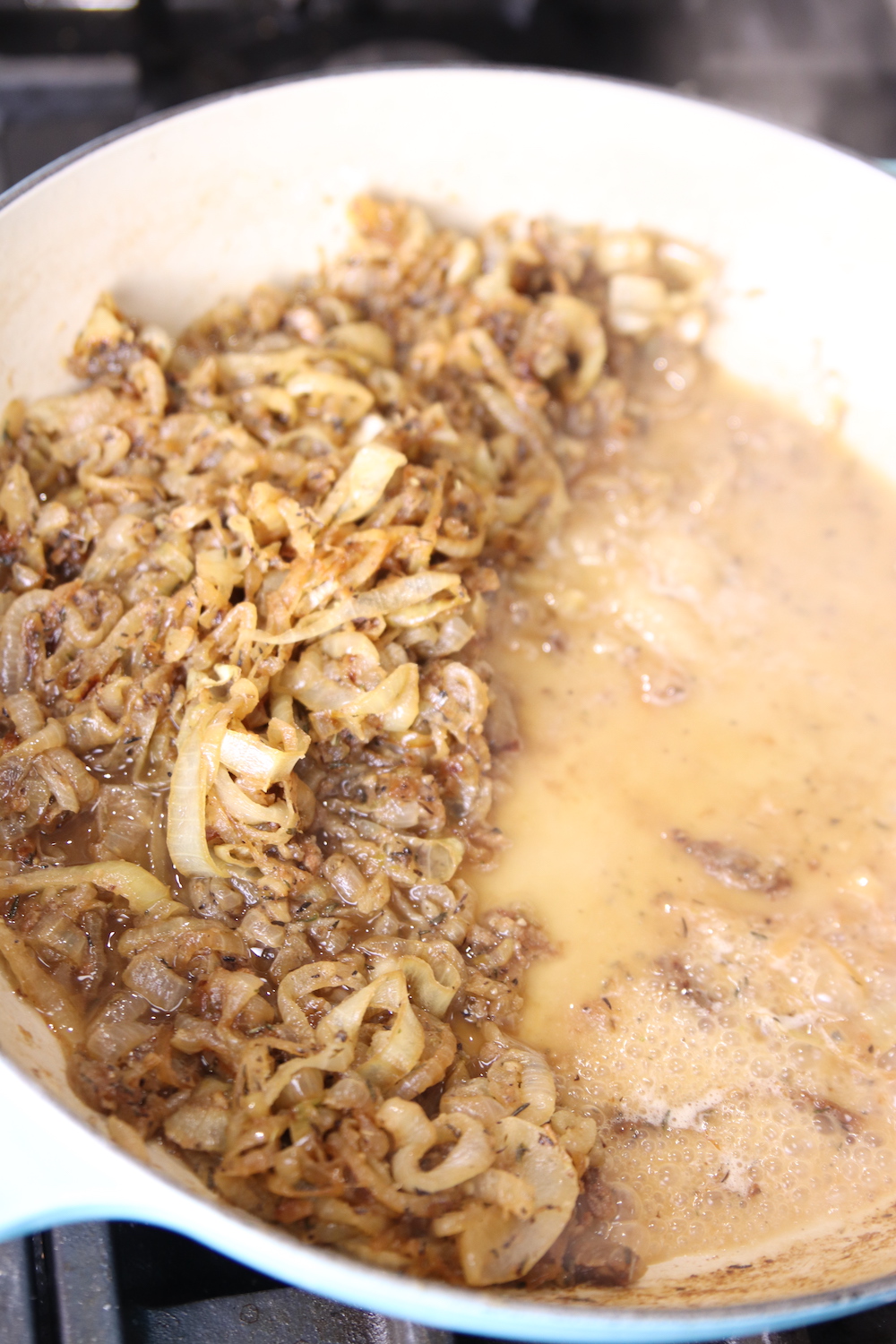 Caramelized onions on one side of the pan adding broth to the other