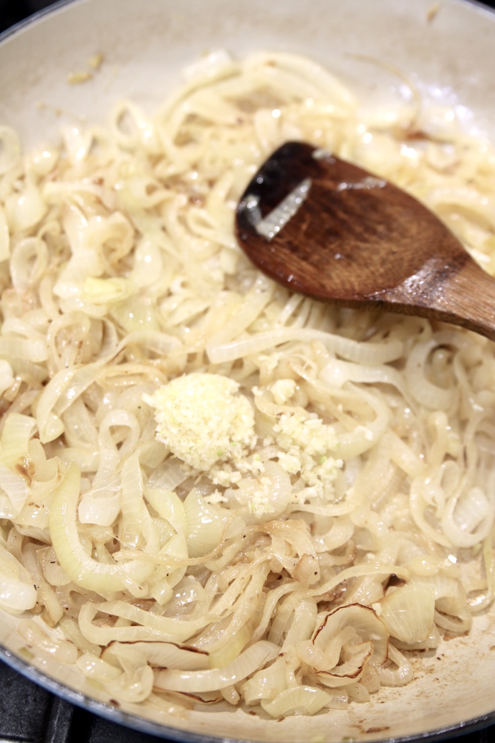 Caramelizing onions with garlic in a pan with a wood spoon