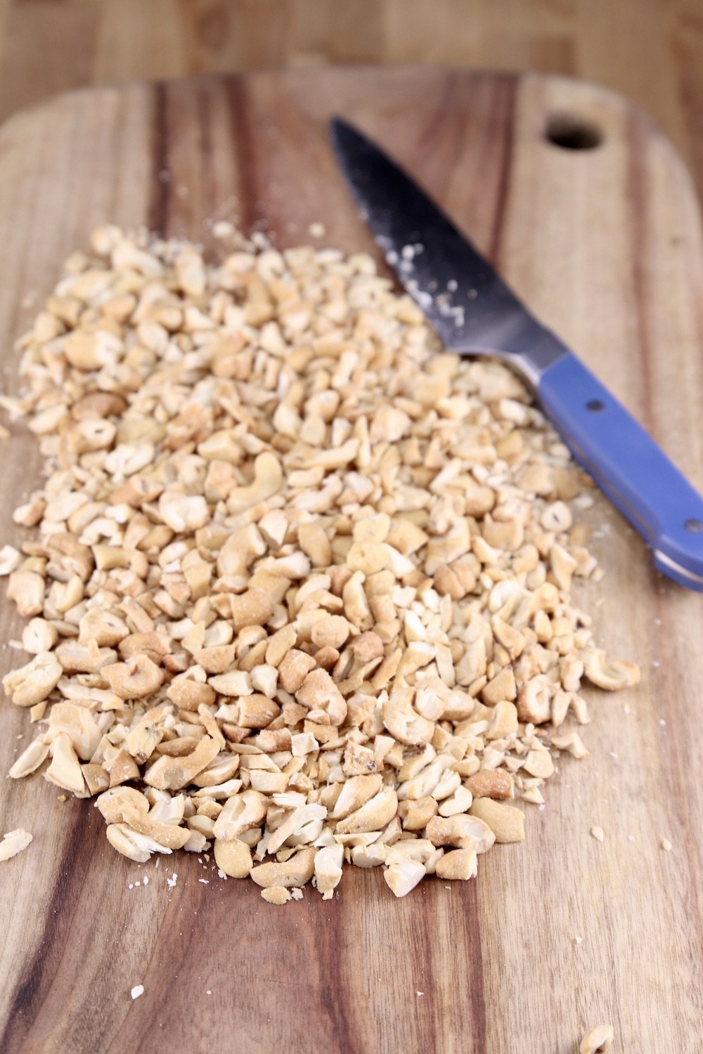 chopped cashews on a cutting board with a knife