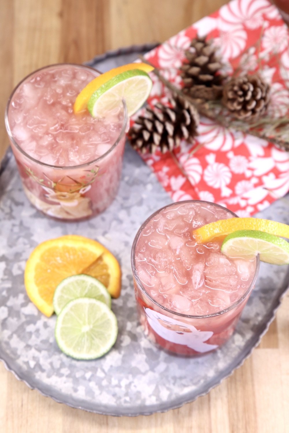 Overhead view of 2 glasses of punch on a platter with pinecones