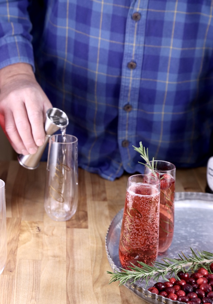 Man pouring triple sec into a champagne glass for cocktails