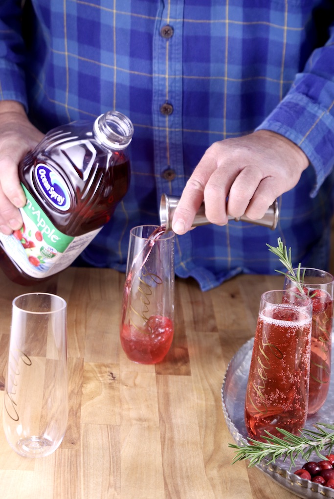 Man pouring cranberry juice into a champagne glass for cocktails