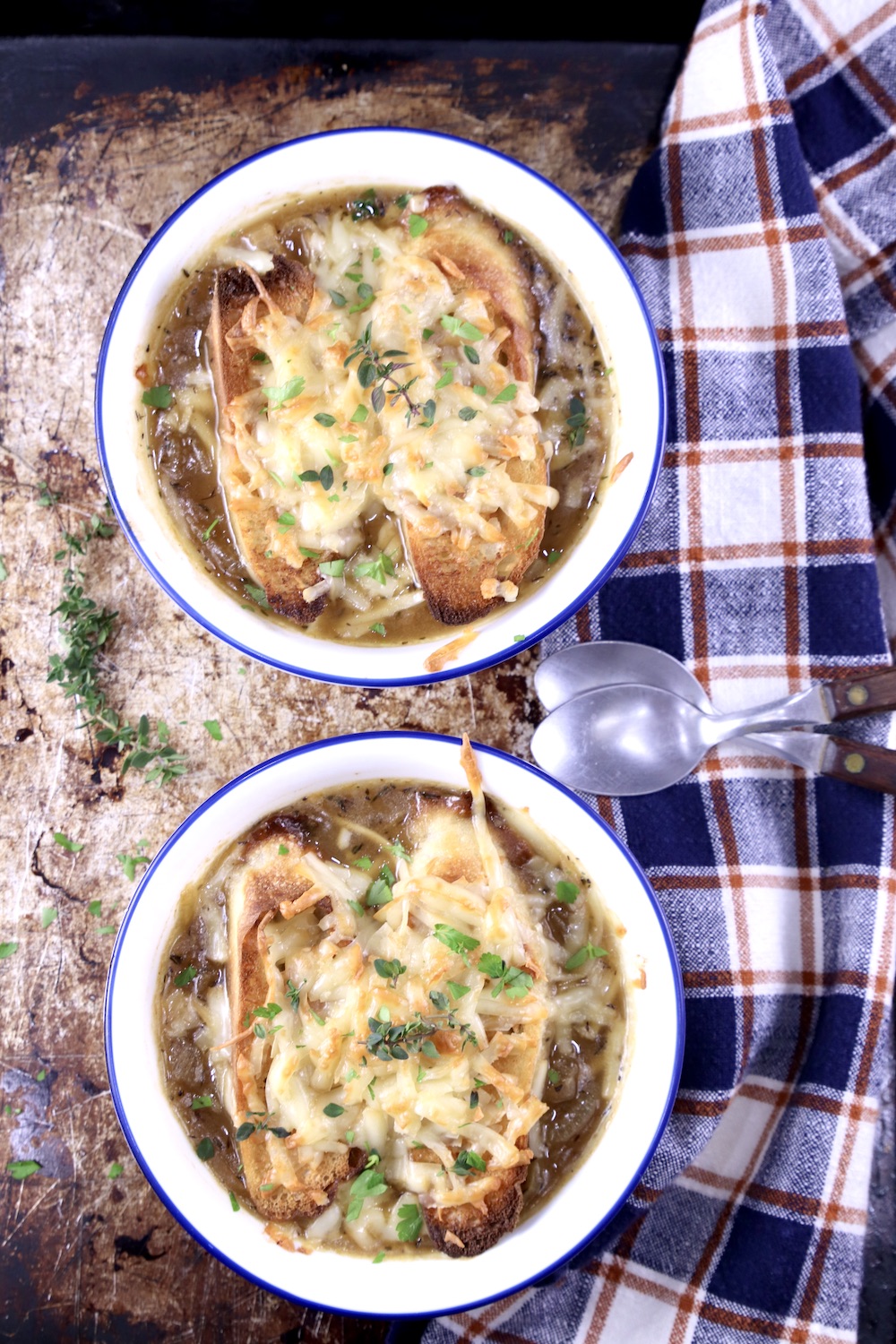 2 bowls of French Onion Soup with toasted baguette and melted cheese, check napkin on the side