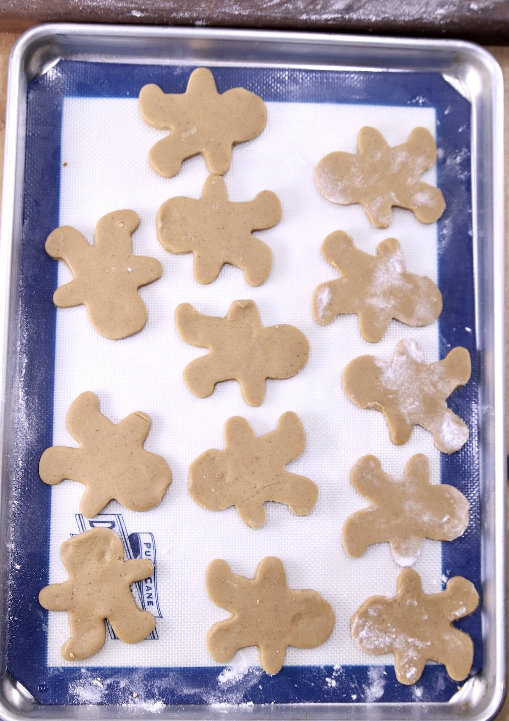 GIngerbread men cookie dough on a silpat lined baking sheet