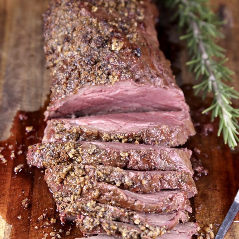 Beef Tenderloin with garlic butter crust, partially sliced on a cutting board