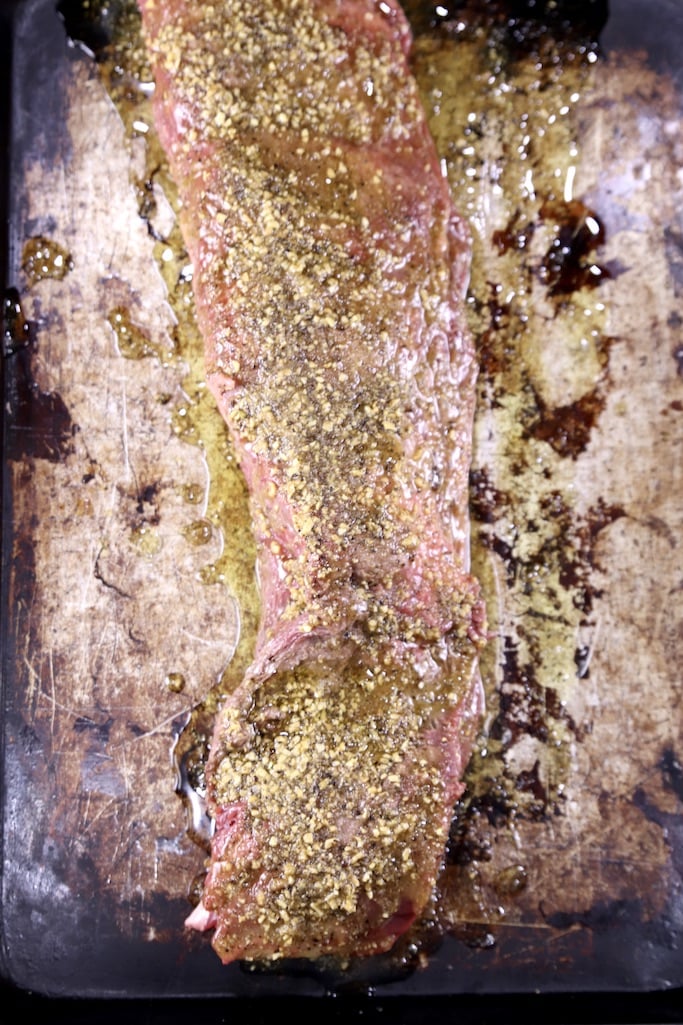 sheet pan with beef tenderloin coated in garlic butter