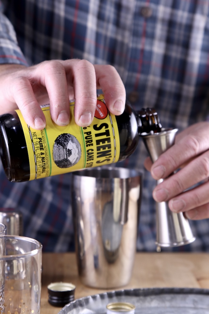 Pouring cane syrup into a jigger for a cocktail