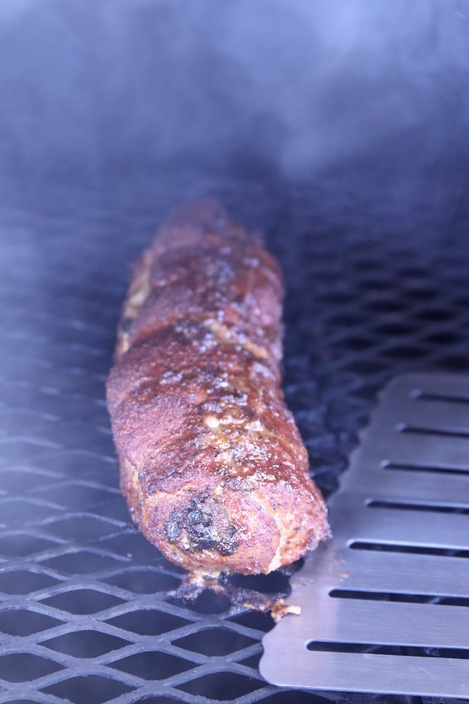 Spatula removing grilled pork tenderloin from the grill