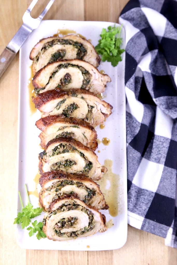 Stuffed Pork Tenderloin on a platter with a blue check napkin to the side