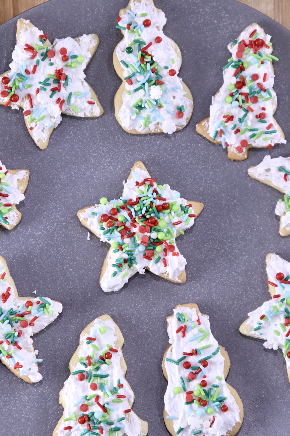 Platter of iced sugar cookies with sprinkles. Christmas shapes - trees, stars, snowmen
