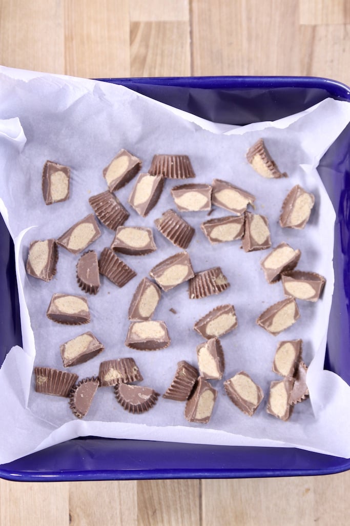 Peanut Butter Cups sliced in half in a parchment lined blue baking pan