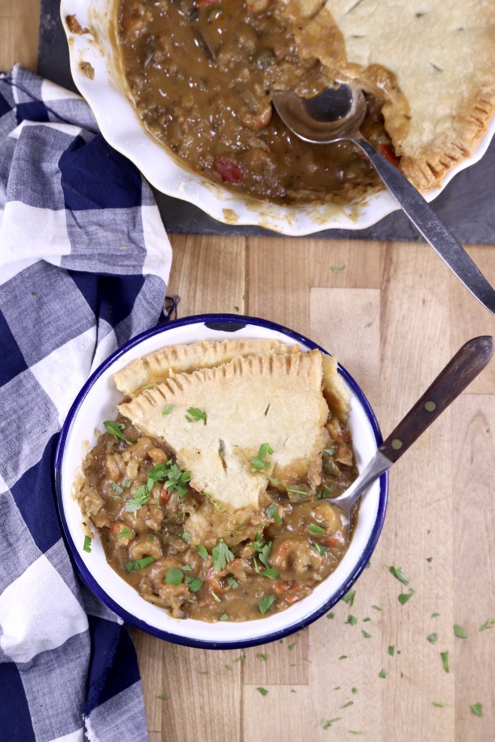 Crawfish Pie in a small bowl with pie plate and a blue check napkin - overhead view