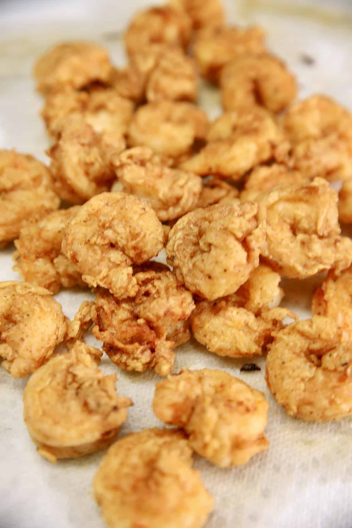 Fried shrimp on a paper towel lined wire rack.